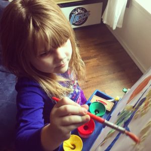 infant girl painting in preschool 